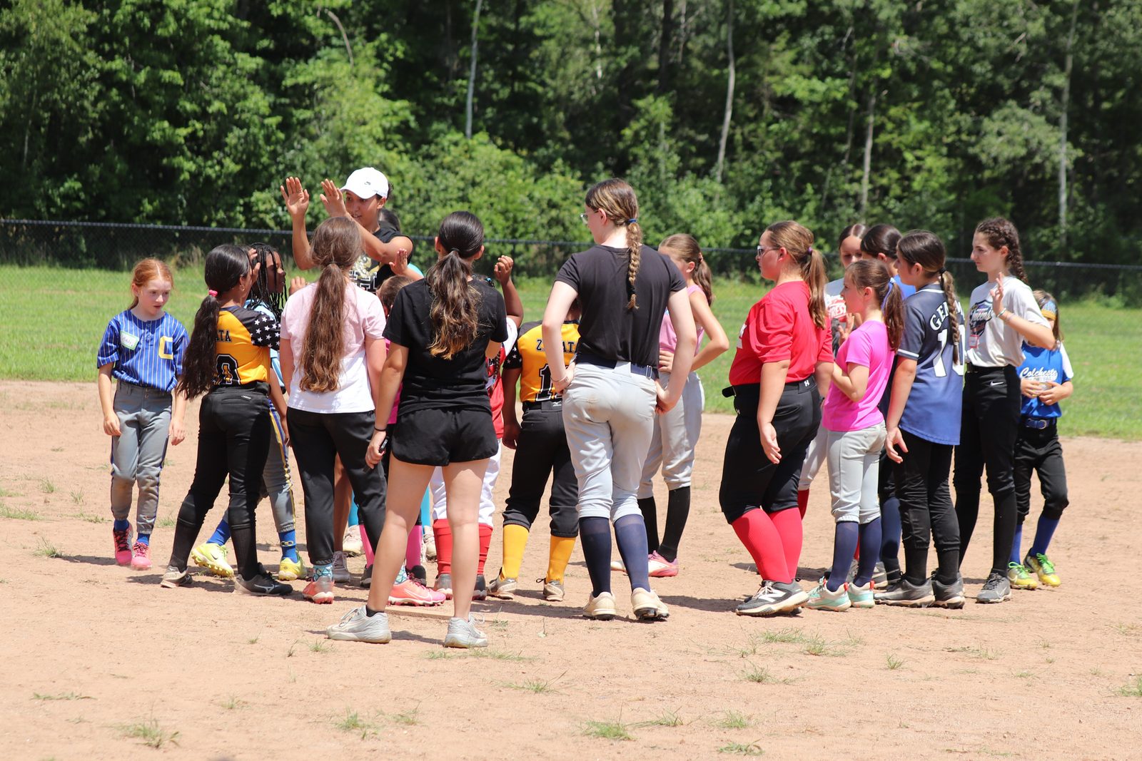Coaches and players trade high-fives in a circle at an East Hartford Softball clinic.