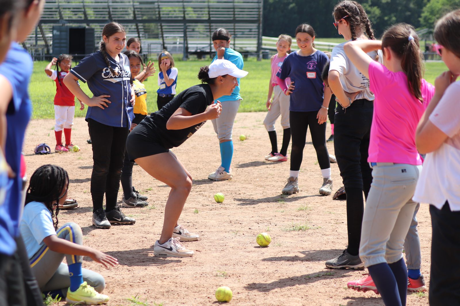 A coach demonstrates fielding position for a circle of players at an EHSB clinic.