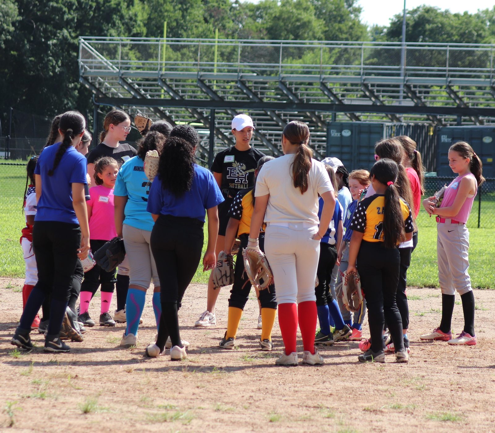 An East Hartford Softball coach talks through the day's plan with players huddled at the EHHS field.